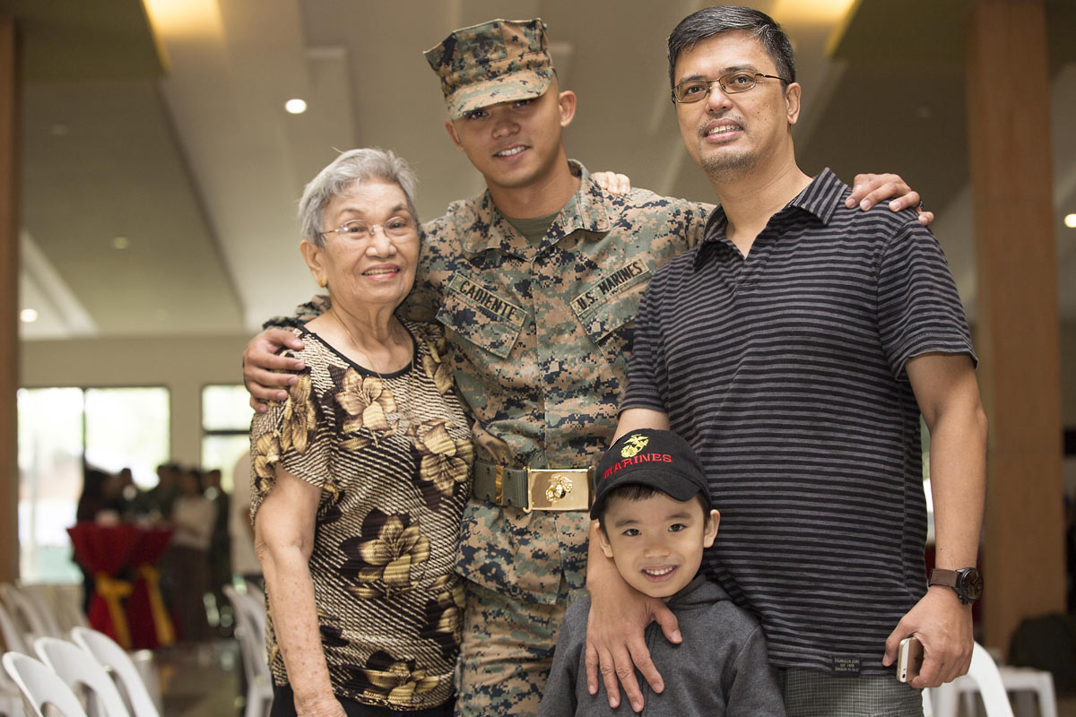 Marine Corps Sgt. Viktor I. Cadiente, a joint fires observer assigned to 3rd Marine Expeditionary Brigade, poses for a photo with his family during the opening ceremony for Amphibious Landing Exercise 2015 at the Philippine Marine Corps Base in Fort Bonif
