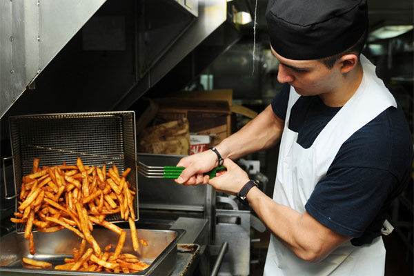 Culinary Specialist 3rd Class Jose Gomez transfers french fries in preparation for chow in the chiefs’ mess of the USS Abraham Lincoln (CVN 72).. (U.S. Navy photo by Mass Communication Specialist Seaman Zachary S. Welch)